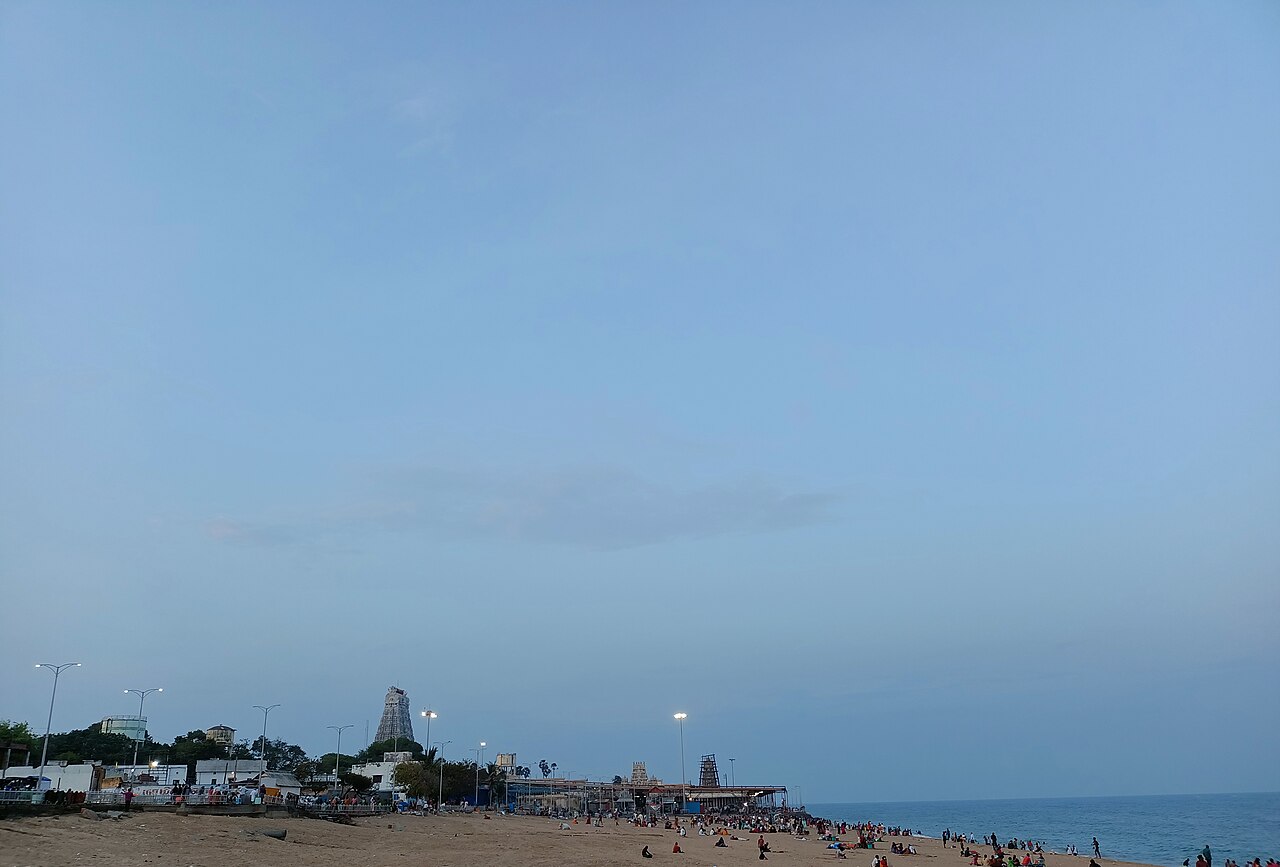 Wide view of Tiruchendur beach at dusk with the temple tower on the skyline